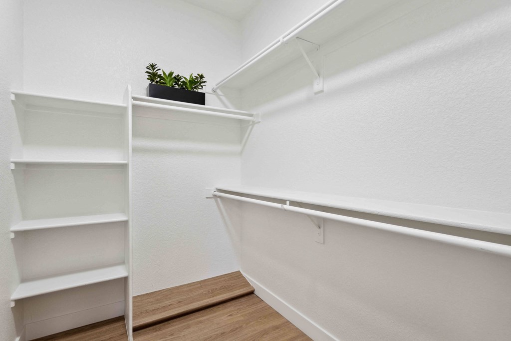 a walk in closet with white walls and shelves and