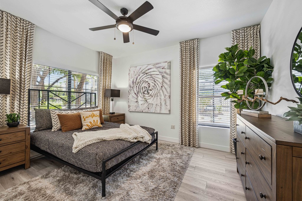 large bedroom at lazo apartments with ceiling fan and windows