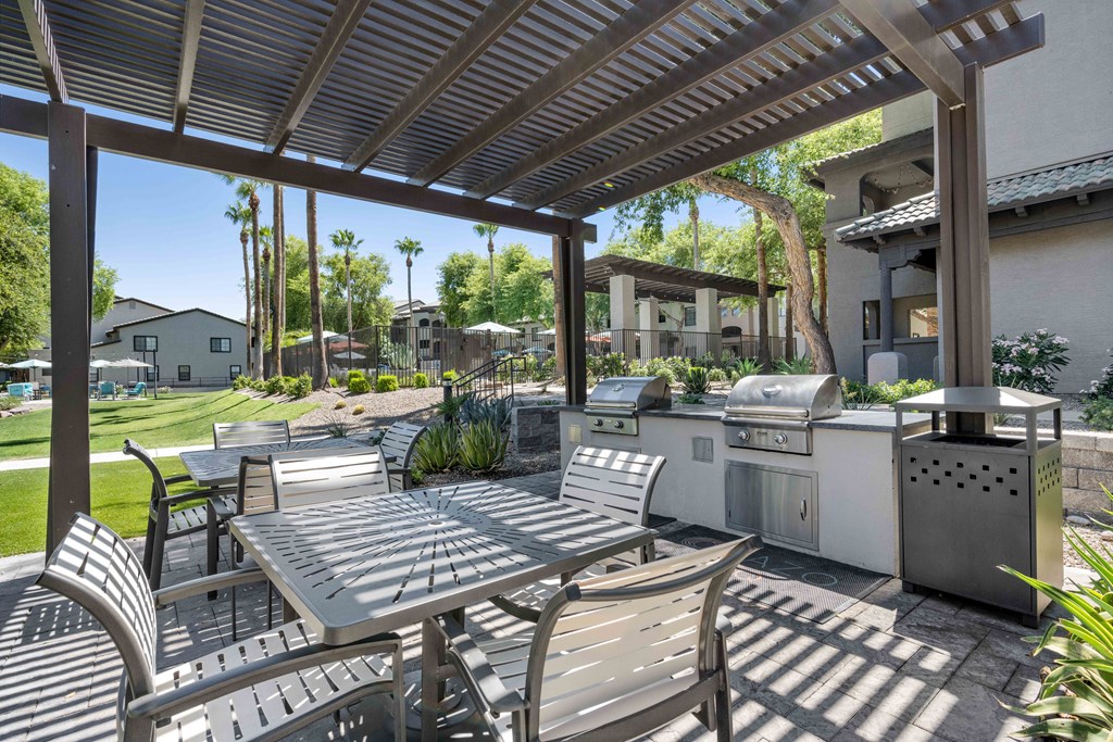 outdoor barbecue grilling area with chairs at lazo apartment homes