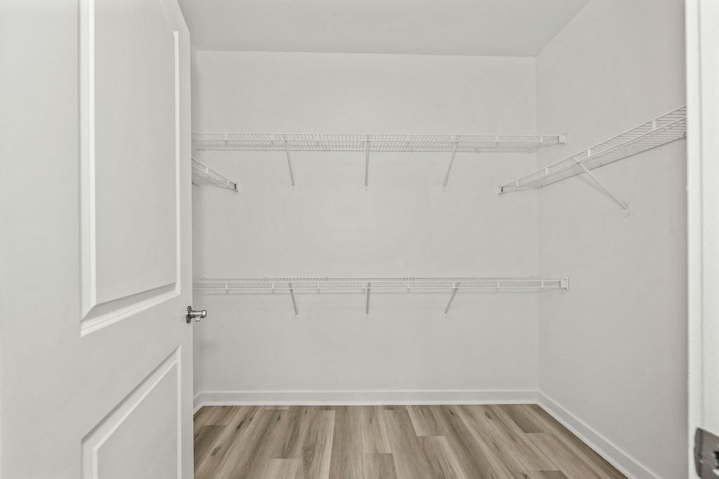 the closet in a bedroom with white walls and wood floors