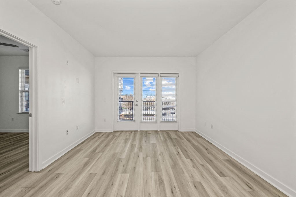 an empty living room with wood floors and a window