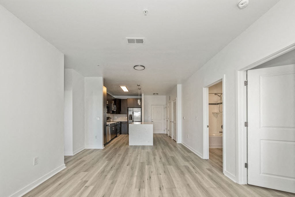 a renovated living room and kitchen with white walls and wood floors