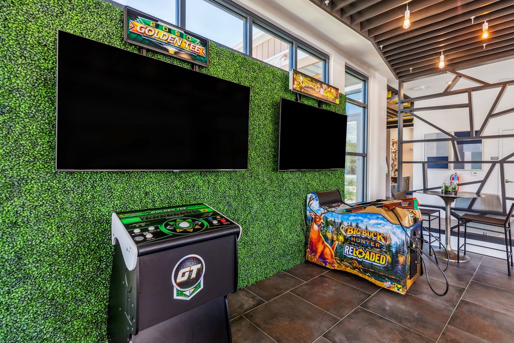 a game room with green astroturf and flat screen televisions