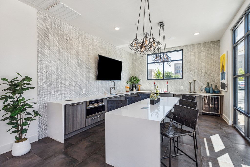 a kitchen with a large white island with two stools and a chandelier
