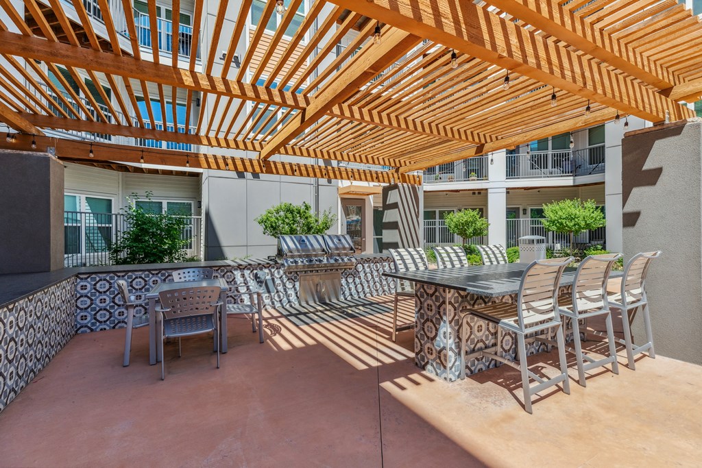 an outdoor patio with a dining table and chairs and a pergola