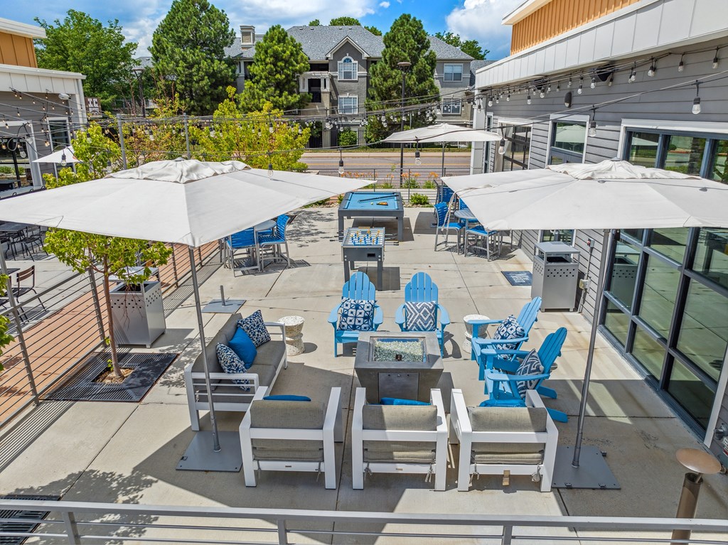 an outdoor patio with blue lounge chairs and white umbrellas