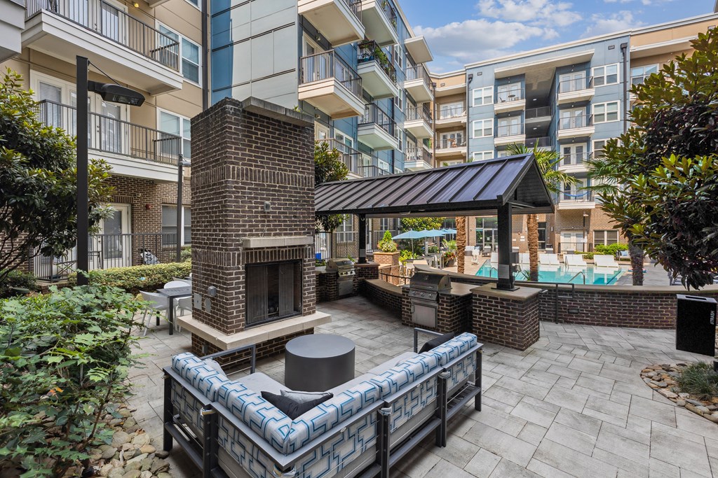a patio with a fireplace and a pool in front of an apartment building