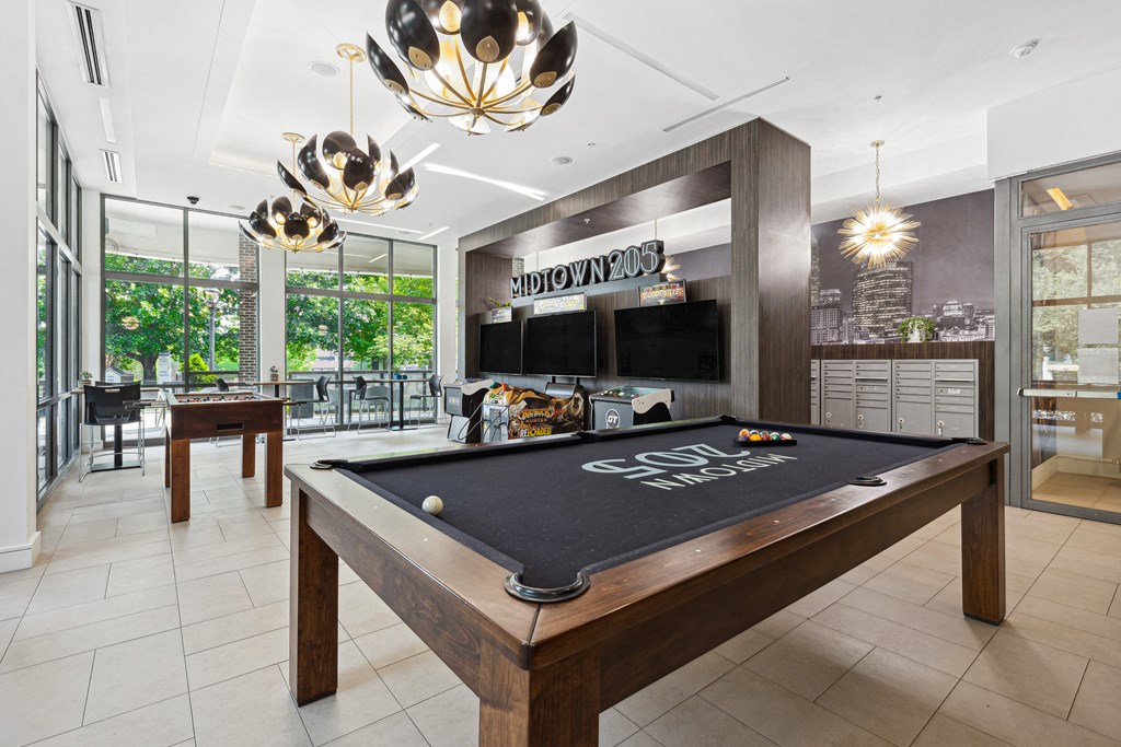 a games room with a pool table and two televisions