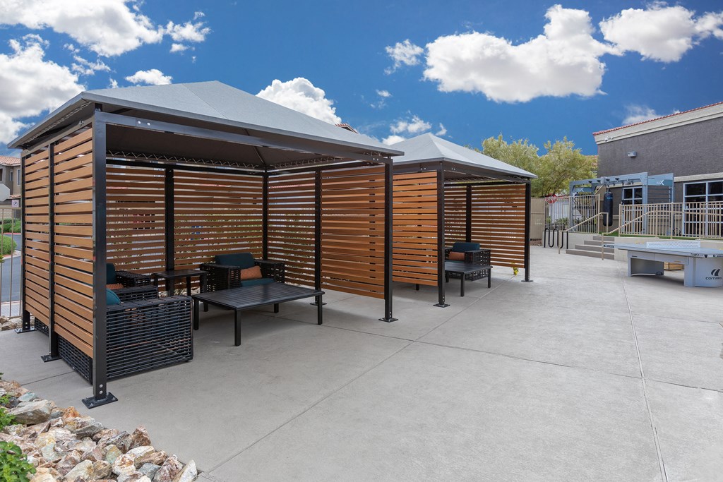 a large patio with tables and chairs and a wooden privacy wall