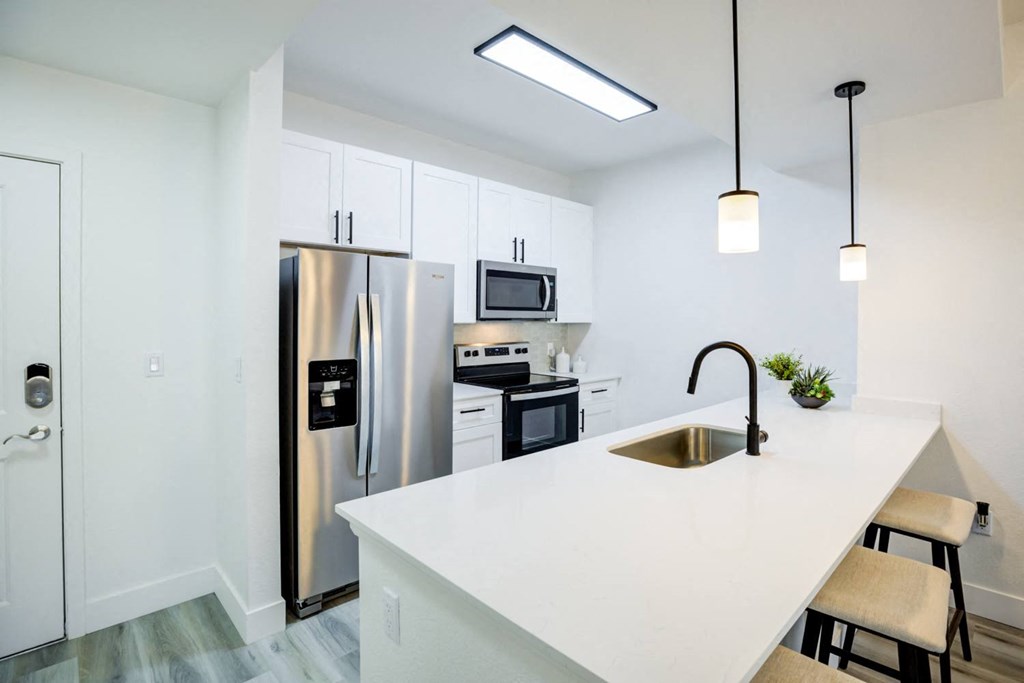 a kitchen with a white counter top and a stainless steel refrigerator