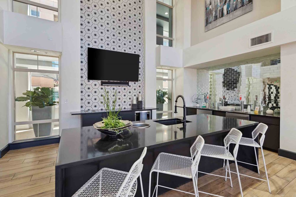 a kitchen with a large center island with a black countertop and white chairs