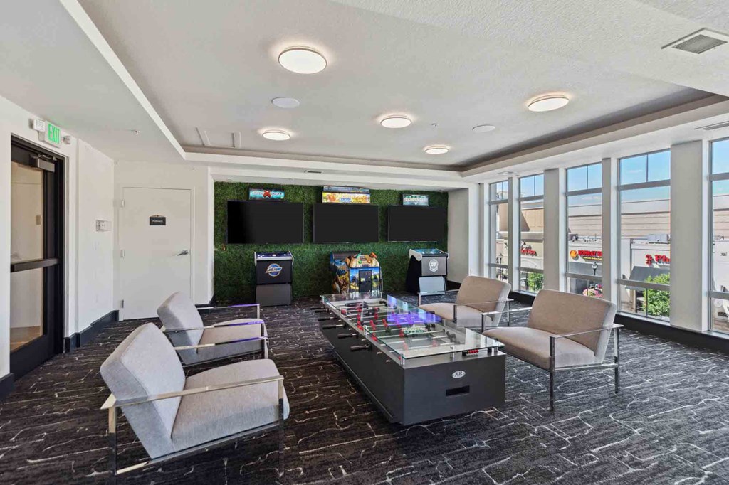 a room with couches and a coffee table with two televisions on the wall and a