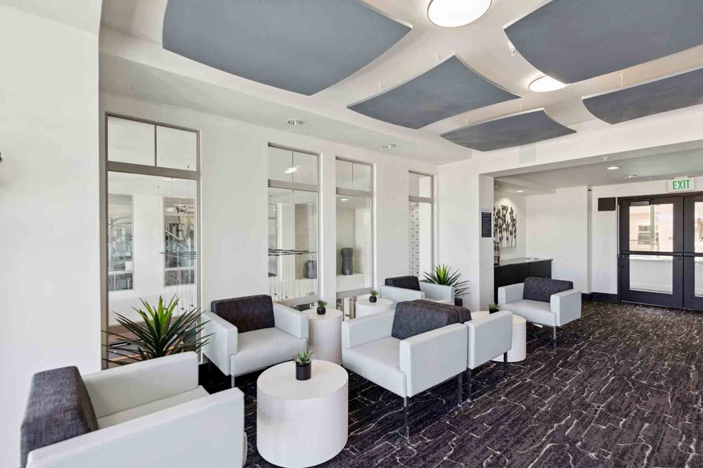 a lobby with white couches and chairs and a black carpet