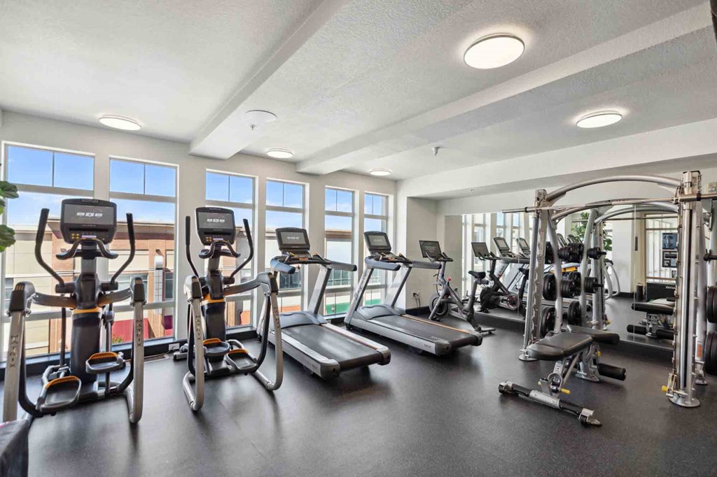 a gym with cardio equipment and windows