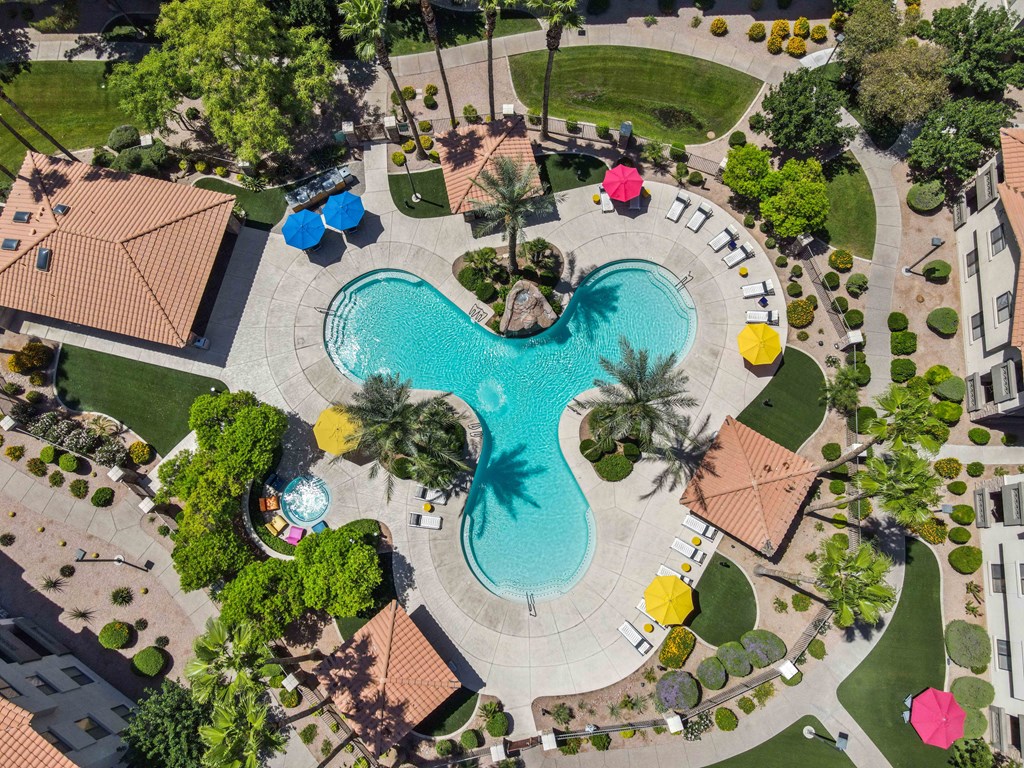 a large swimming pool surrounded by trees and umbrellas