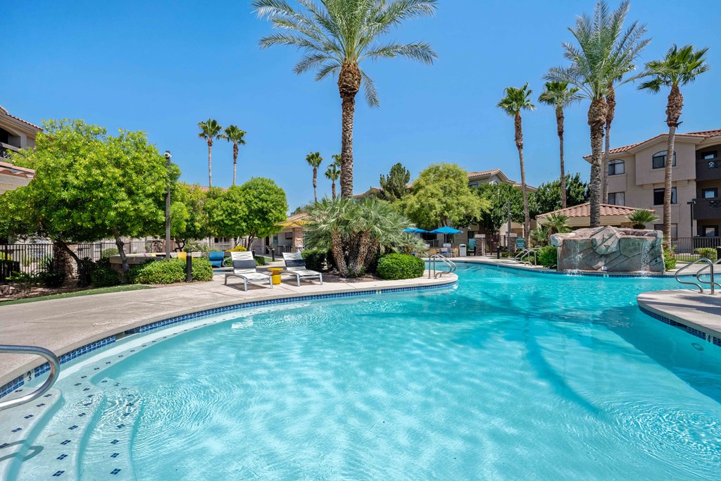 a large swimming pool with lounge chairs and palm trees in tempe arizona