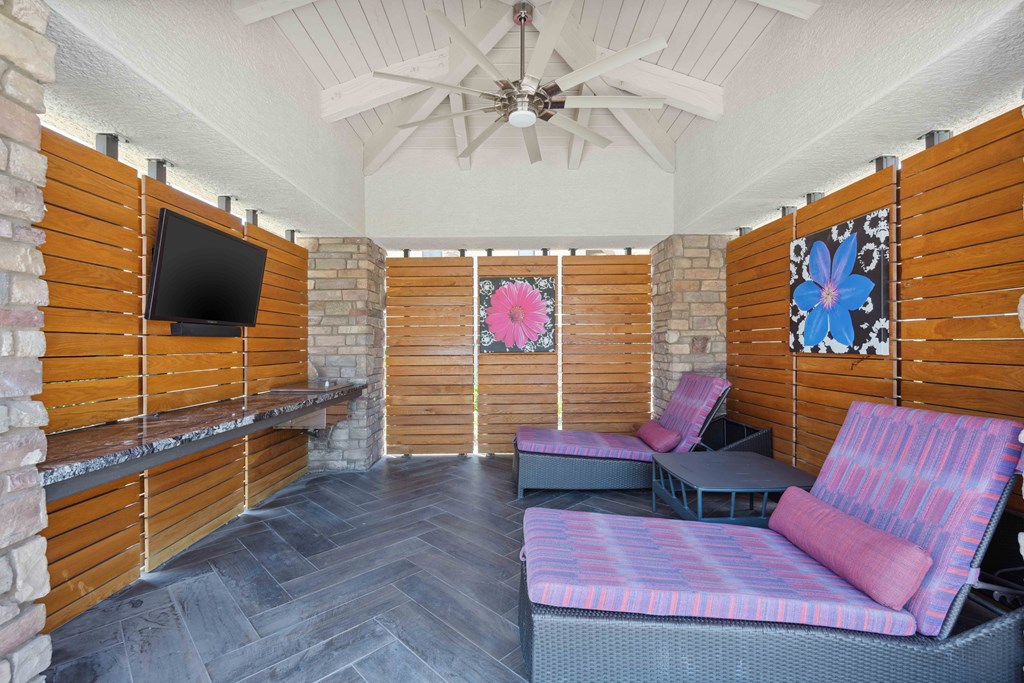 pool cabana seating area with couches and a television