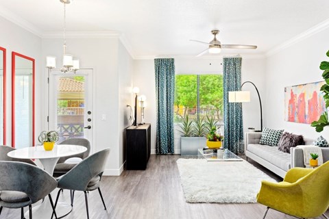 A living room with a white couch, a yellow chair, and a dining table with chairs.