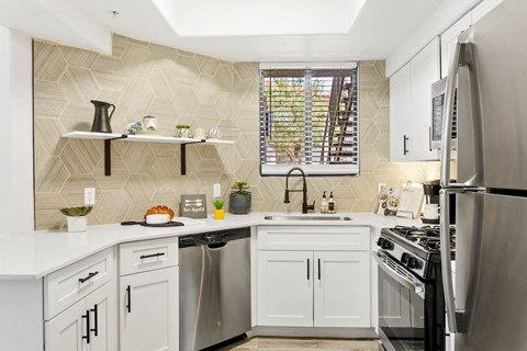 A kitchen with white cabinets and a stainless steel refrigerator.