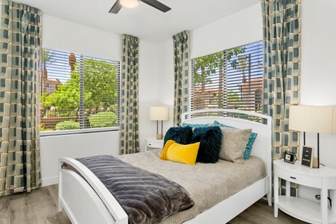 A bedroom with a bed, nightstand, and window with curtains.