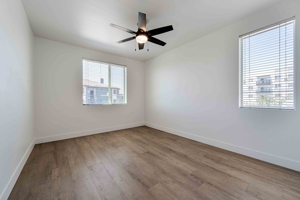 an empty living room with wood floors and a ceiling fan