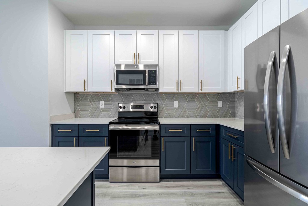 a kitchen with blue and white cabinets and stainless steel appliances