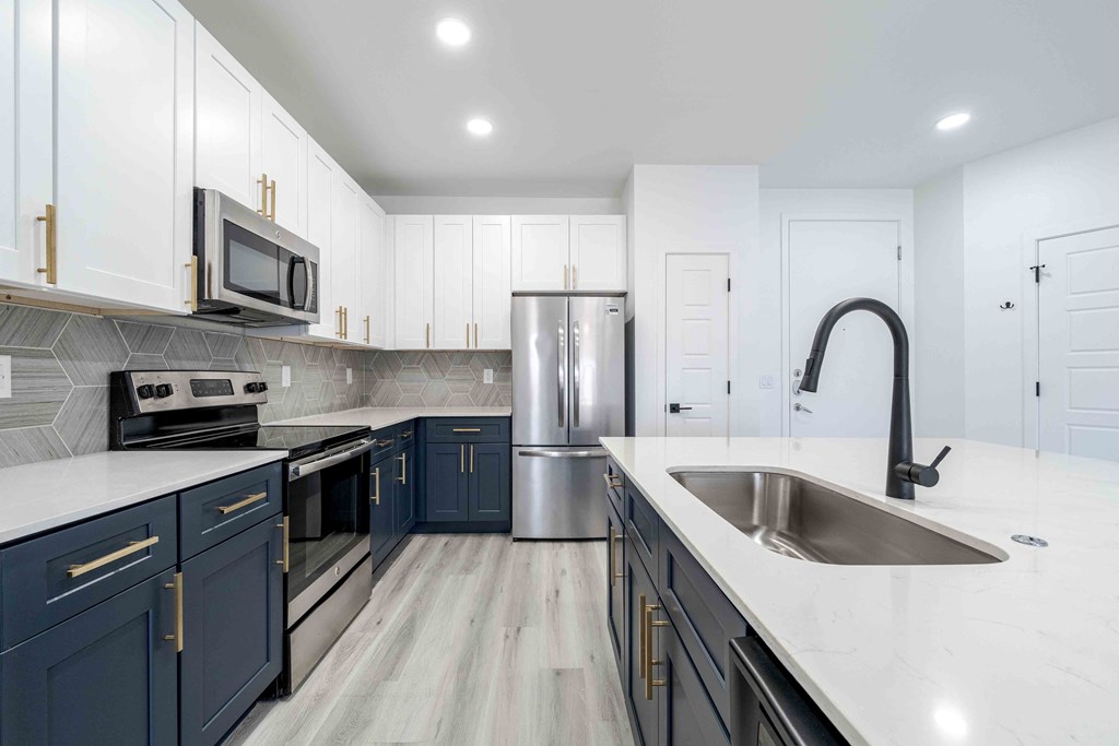 a kitchen with blue and white cabinets and stainless steel appliances