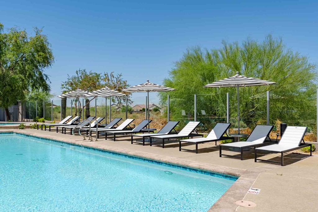 a swimming pool with chaise lounge chairs and umbrellas