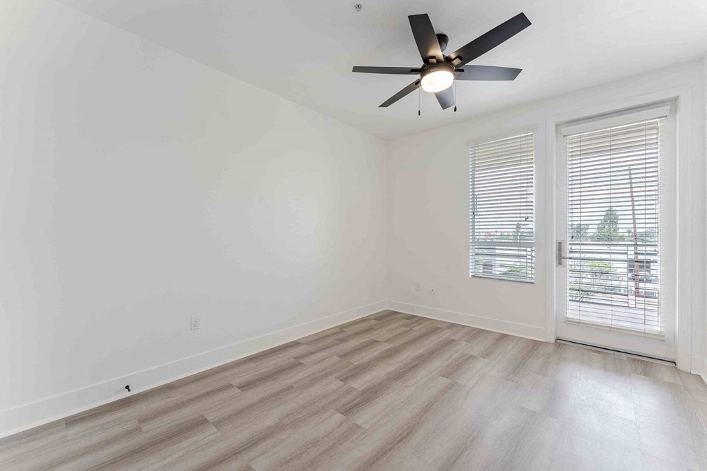 an empty living room with white walls and a ceiling fan