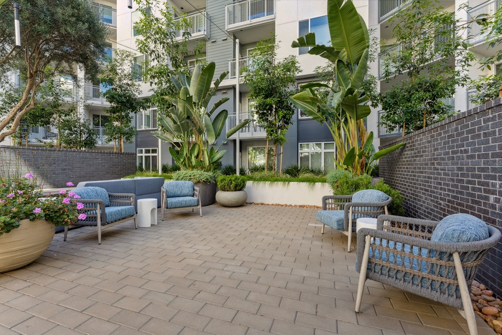 a patio with furniture and plants in front of an apartment building