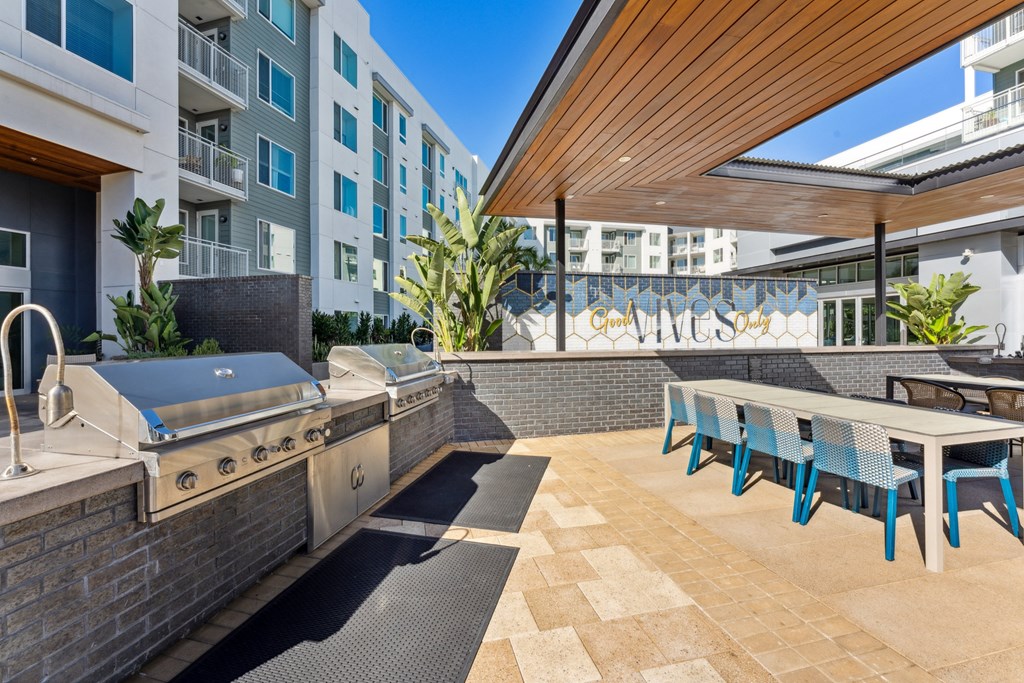 a patio with a barbecue grill and a table with chairs