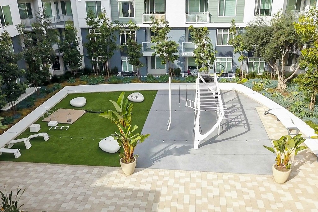 a large yard with a swing set in front of an apartment building