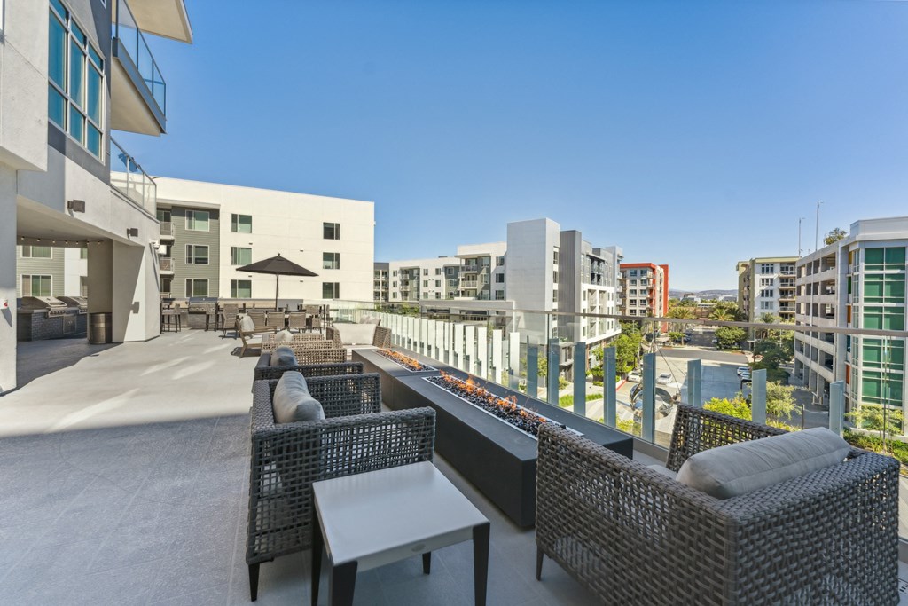 a rooftop terrace with chairs and tables and buildings in the background