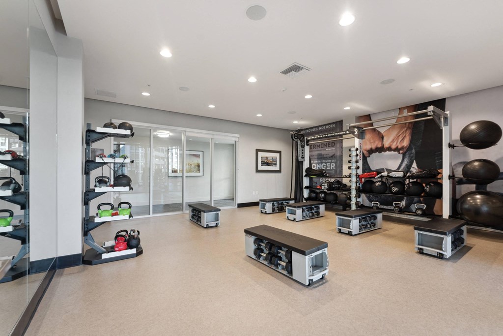 a workout room with weights on the floor and a large wall mural of a gym