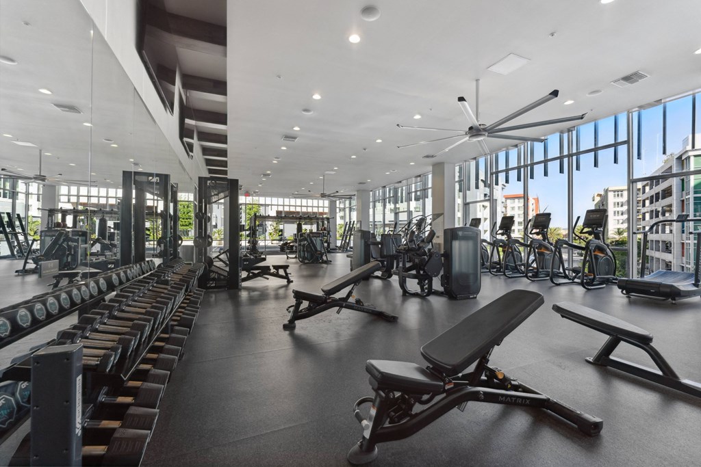 a gym with cardio machines and other exercise equipment in a building with large windows