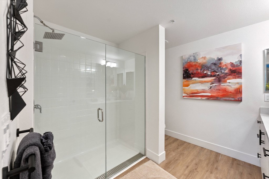a bathroom with a glass shower and a painting on the wall