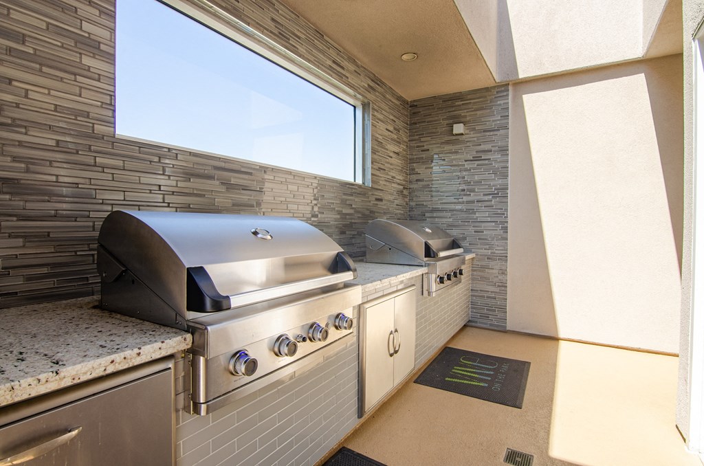 an outdoor kitchen with two grills and a window