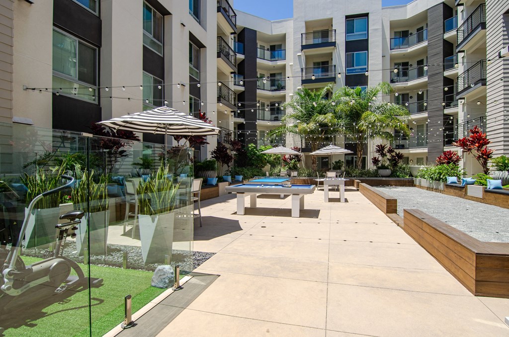 an outdoor patio with tables and umbrellas in an apartment building