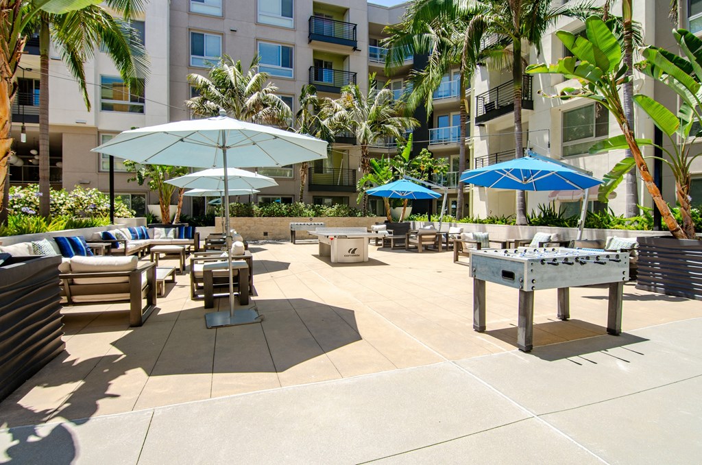 a large patio with tables and umbrellas at an apartment building