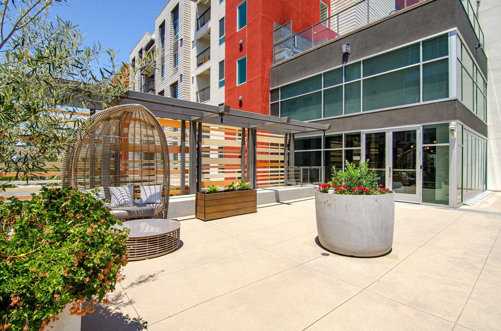 a patio with a gazebo and plants in front of a building