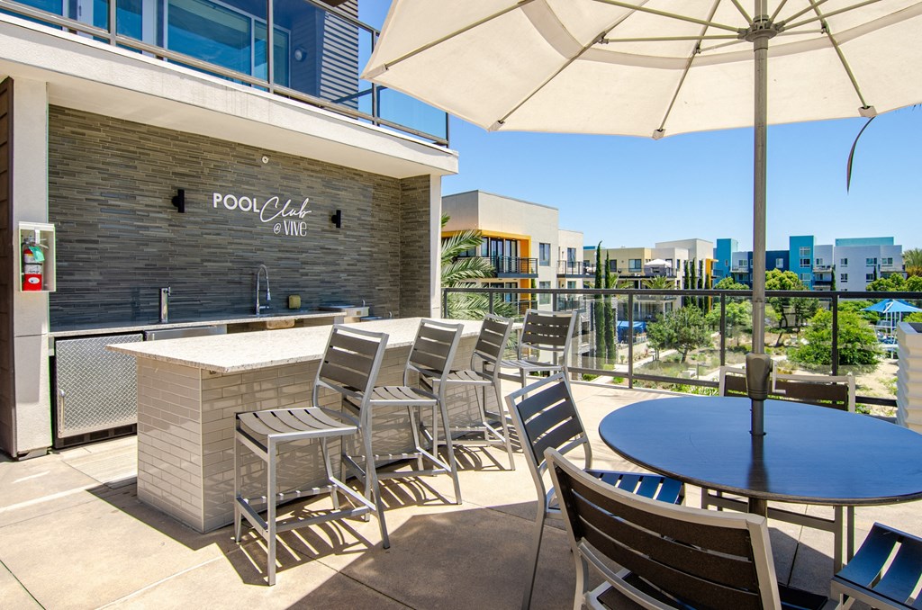 a patio with a bar and tables with chairs and umbrellas