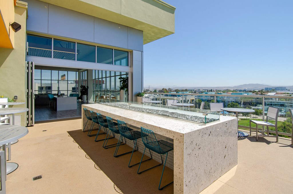 a bar with blue chairs in front of a building with views of the city