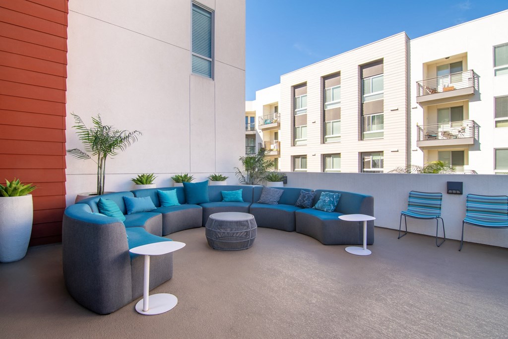 a patio with blue couches and chairs and tables
