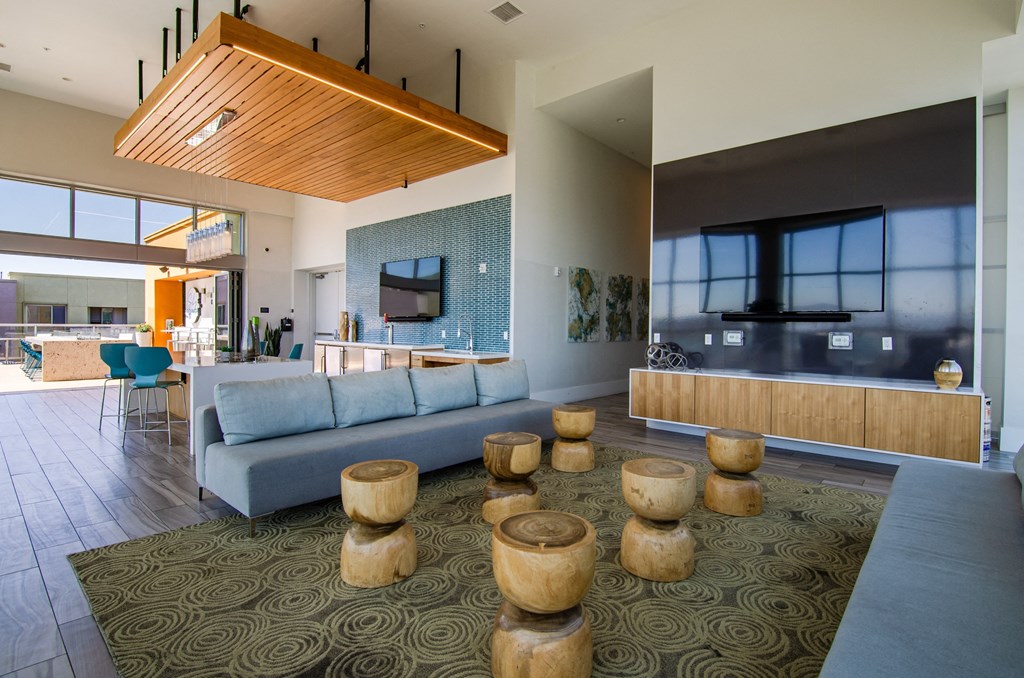 a large living room with a blue couch and wooden stools