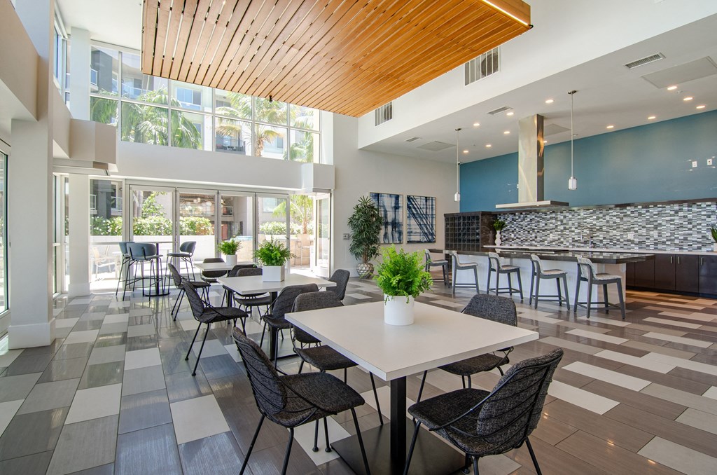 a communal dining room with tables and chairs in a building with large windows
