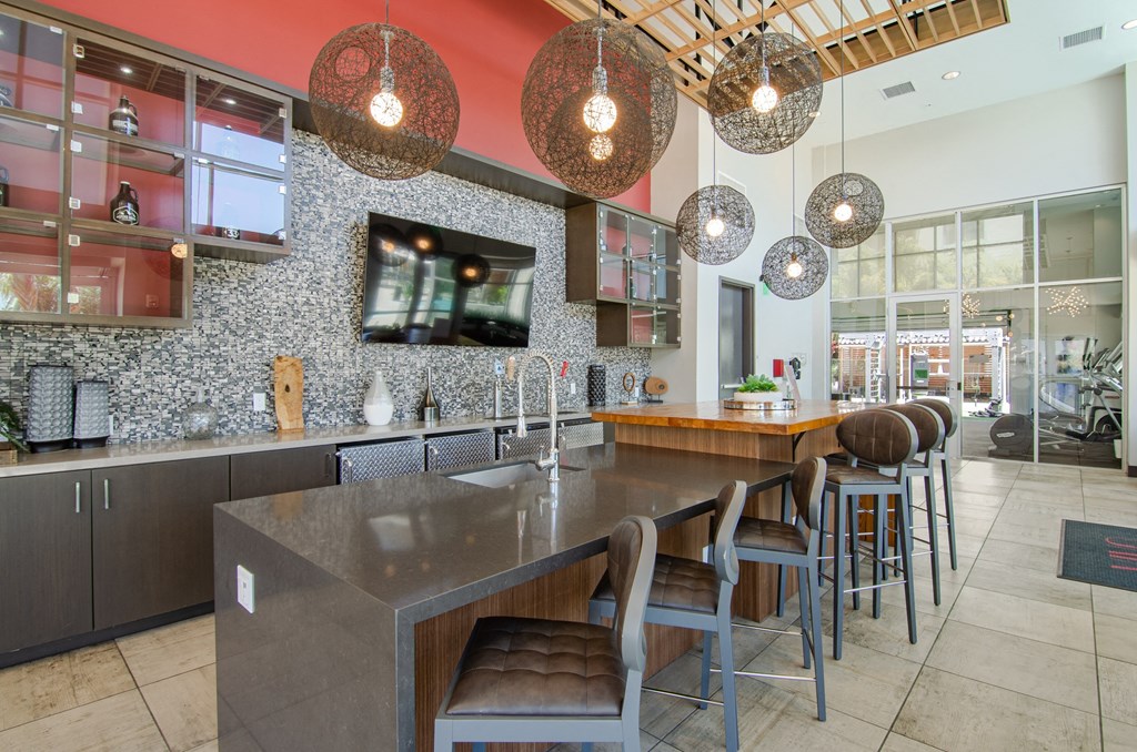 a kitchen with a long counter and chairs and a tv