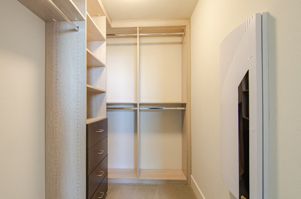 a walk in closet in a home with shelves and a refrigerator