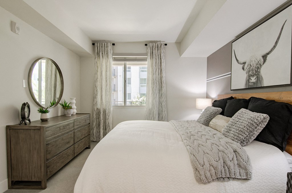 a bedroom with a large bed and a mirror and a window