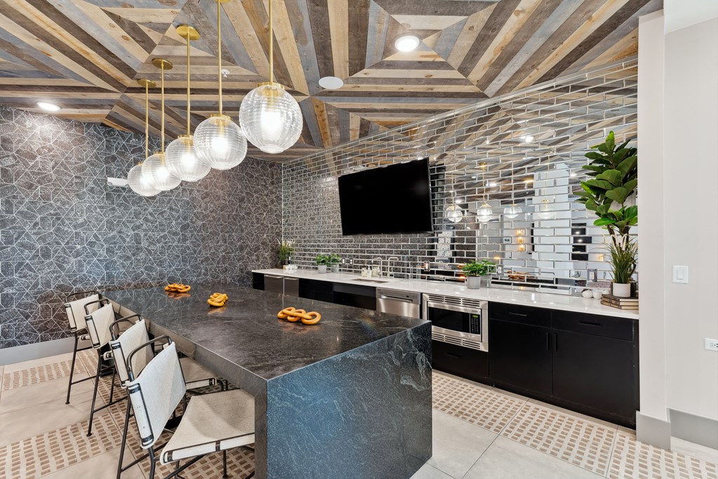 a kitchen with a large island with a black granite countertop and a tv on the wall