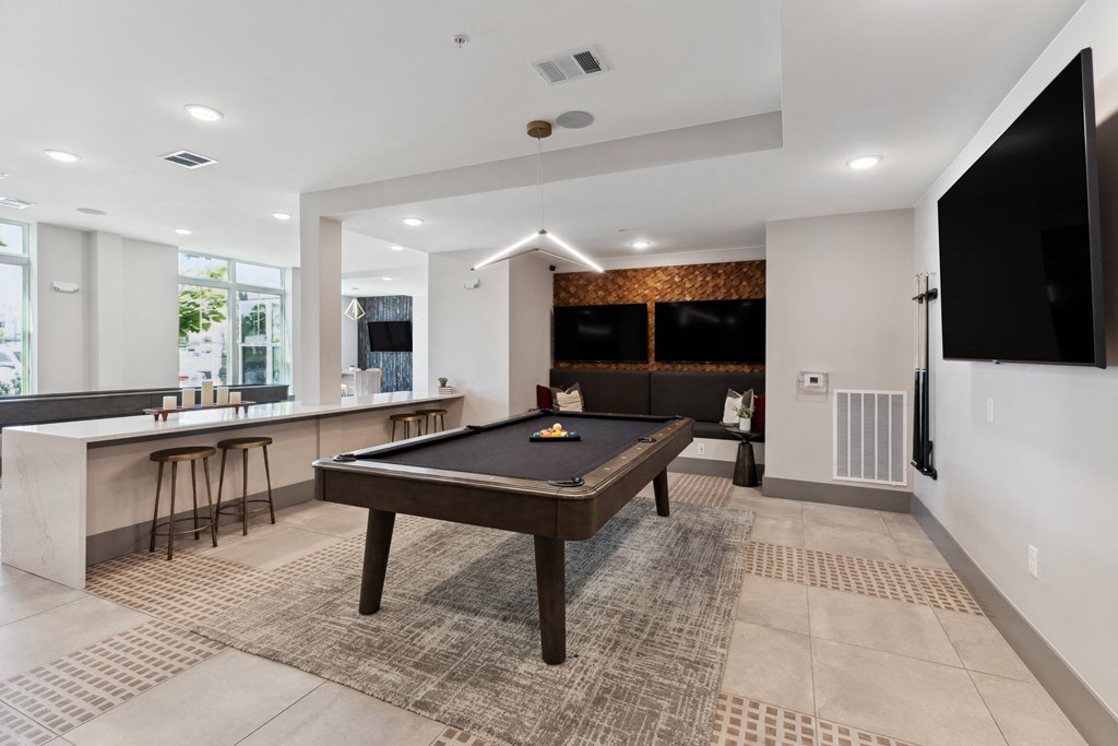a spacious game room with a pool table and a bar with stools